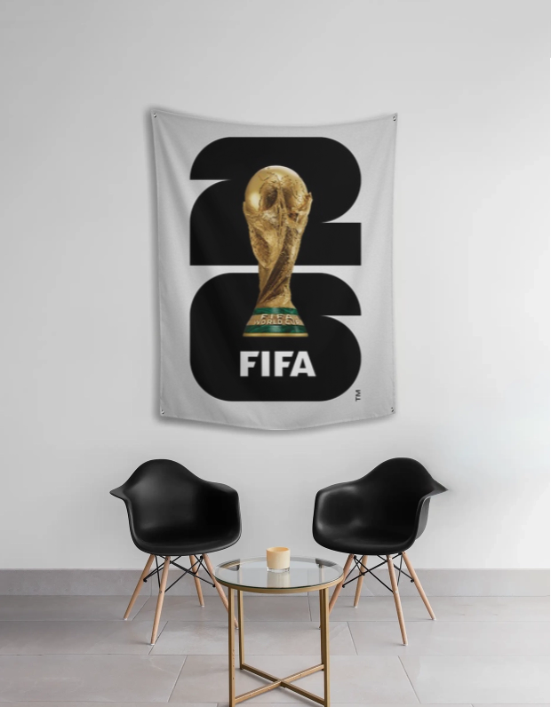 FIFA World Cup tapestry with trophy design on a wall in a room with black chairs and a small table.